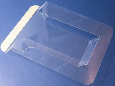 Prospekthalter - Faltbarer Stanzteil aus transparenter Kunststoff-Hartfolie, mit Klebestreifen für Montage auf Glaselement